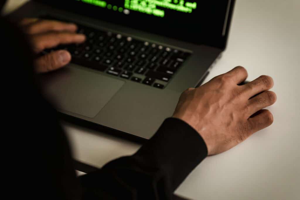 Close up of a person wearing a black sweater typing on their laptop
