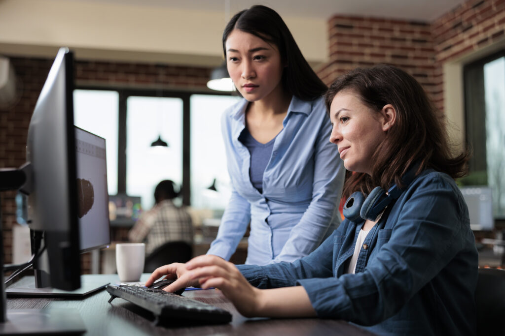 Two female workers looking at a monitor, smiling