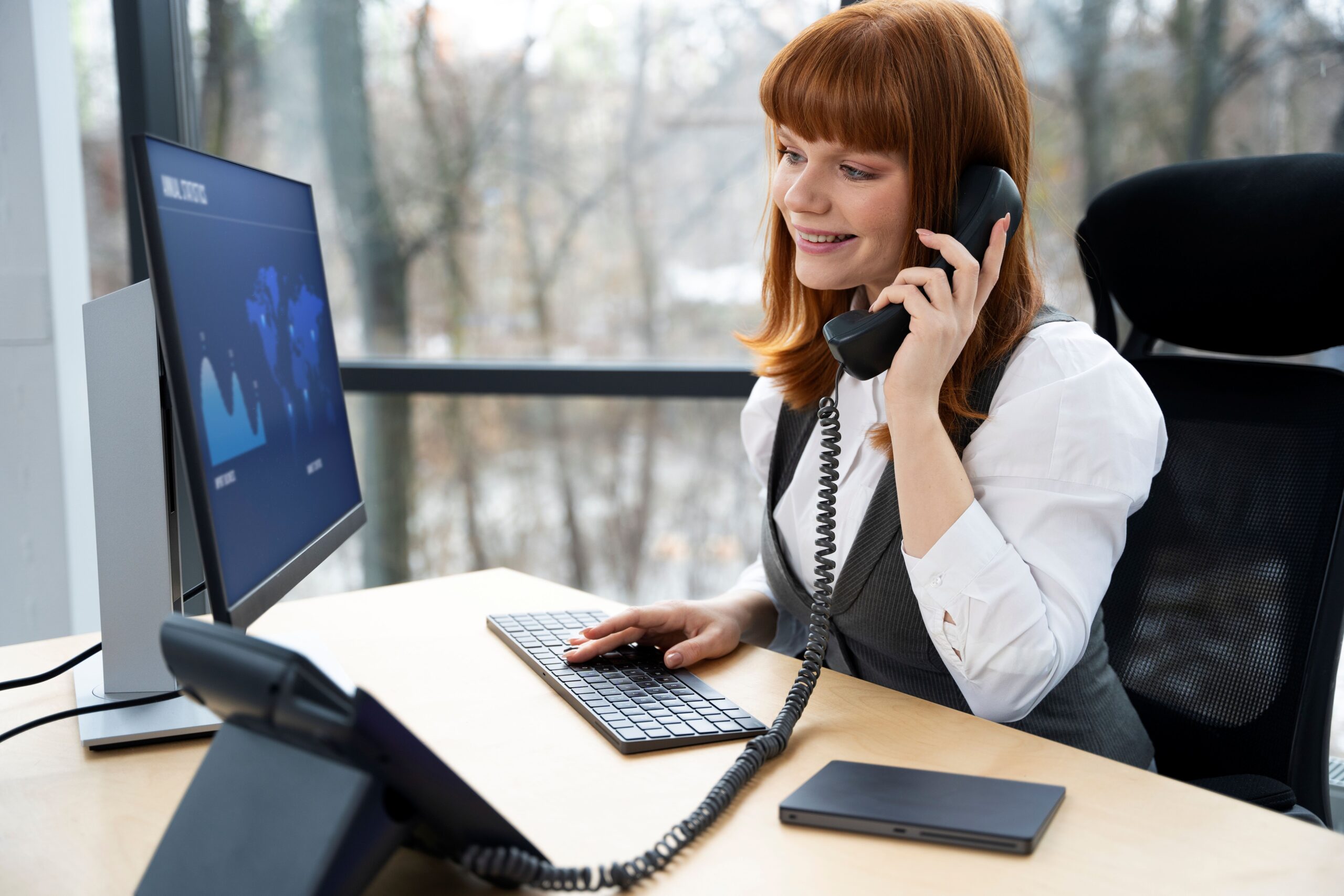 Woman holding a phone in front of computer Woman holding a phone in front of computer