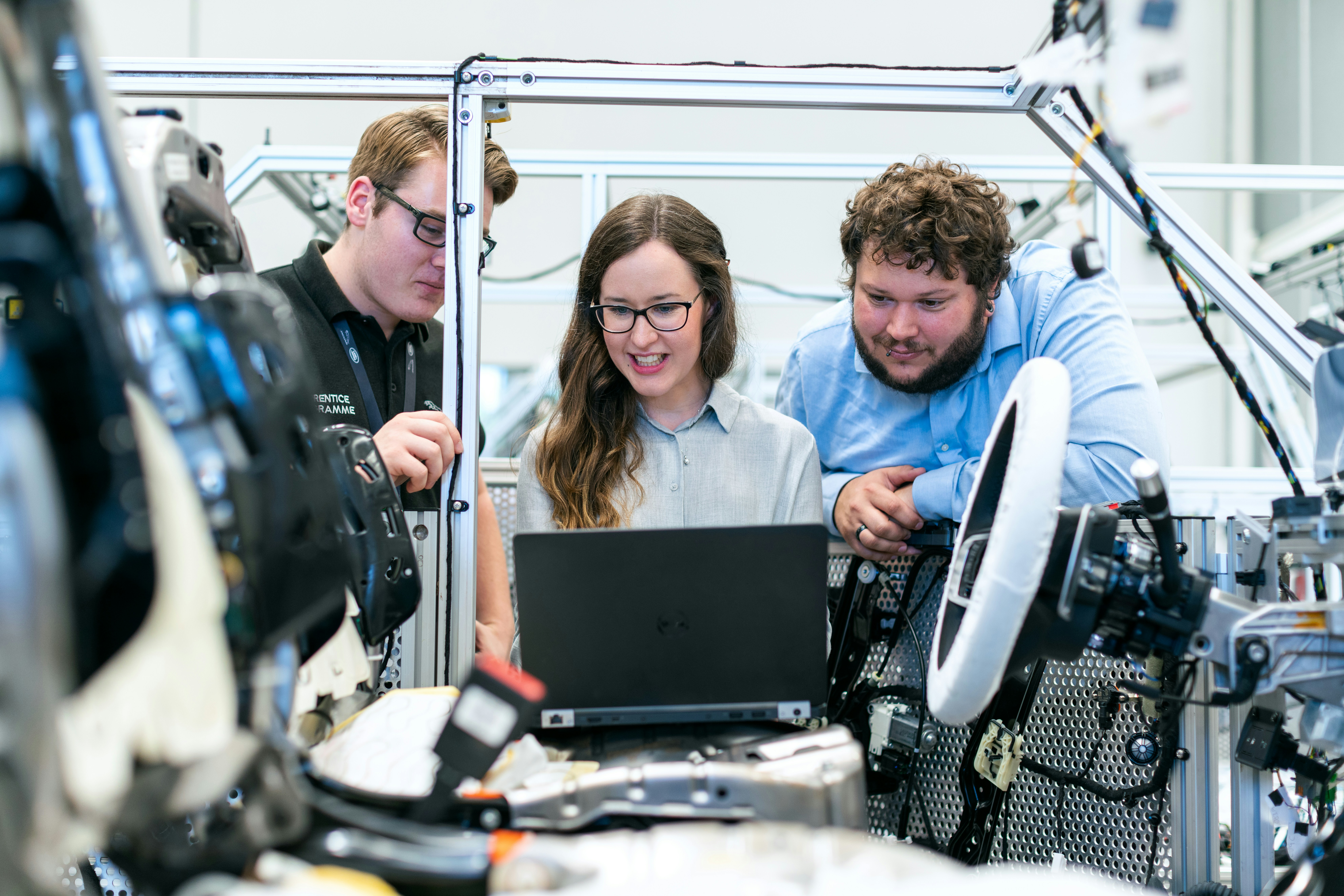 Three engineers in a car manufacturing facility using laptop.